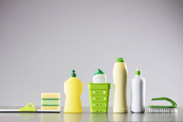 House and office cleaning up theme.  Set of different colorful cleaning products in bottles and sponges and brush on gray background. - Photo, Image