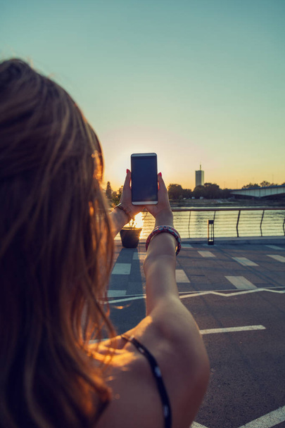 Chica usando el teléfono celular en la ciudad / entorno urbano - cerca del río
. - Foto, imagen