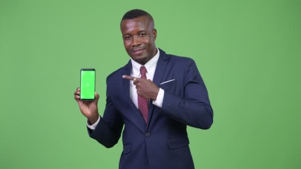 Young happy African businessman showing phone and giving thumbs up - Záběry, video
