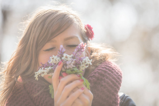 Roztomilá mladá dívka vonící pěknou kytici květin v přírodě. - Fotografie, Obrázek