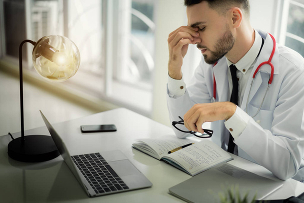 Doctors are making serious faces and stressed about work. The doctor is feeling a headache at work and feeling stressed in treating the patient. - Photo, image