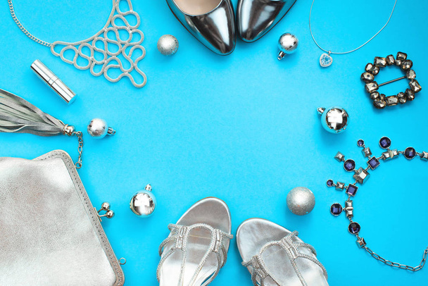 Christmas Set of fashion accessories flat lay shoes handbag necklace jewelry lipstick buckle silver color on blue background. Top view copy space - Photo, Image