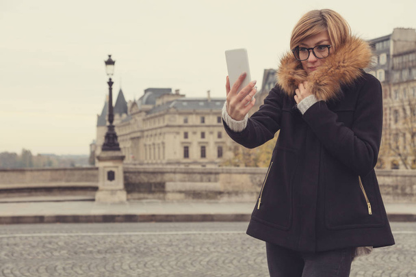 Χαριτωμένο νεαρή γυναίκα που χρησιμοποιούν κινητό τηλέφωνο στο Παρίσι, Γαλλία. - Φωτογραφία, εικόνα