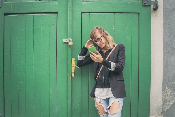 Ładna kobieta trzymając telefon w środowisku miejskim. - Zdjęcie, obraz