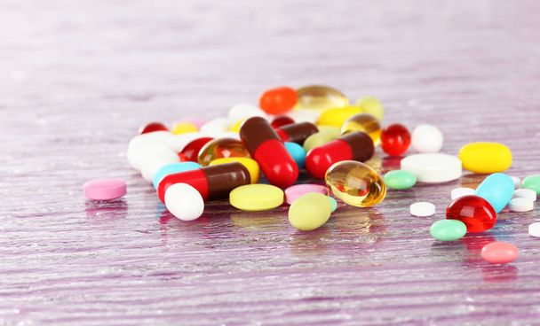 Assortment of pills, tablets and capsules on purple background - Foto, Imagen