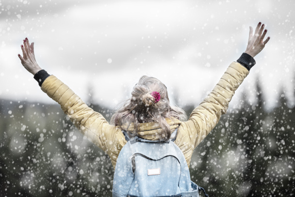 Meisje met de armen wijd open verwacht van de sneeuw in de natuur. - Foto, afbeelding