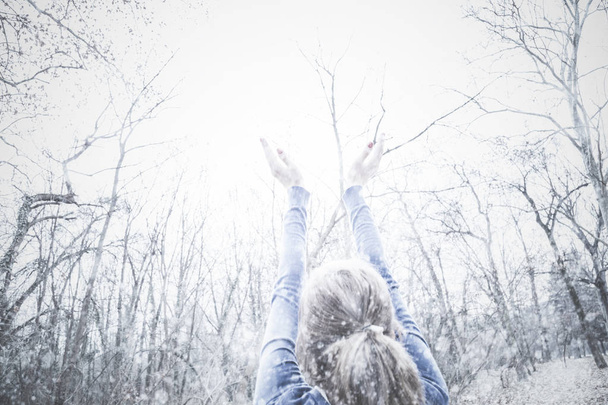 シーズン最初の雪を期待して空気中の手を持つ少女. - 写真・画像