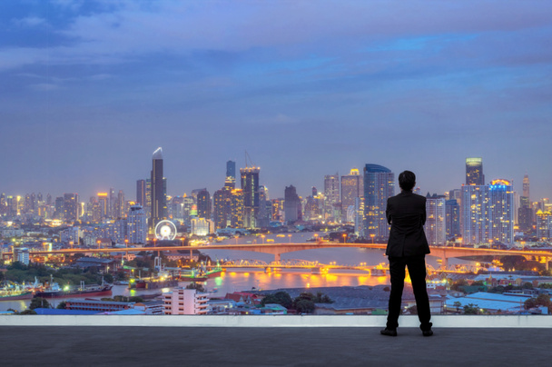 Αντίληψη της όρασης. Επιτυχημένος επιχειρηματίας στέκεται με τα χέρια σταυρωμένα στο στήθος, στην κορυφή του κτιρίου και βλέπουν στον ορίζοντα cityscape τη νύχτα - Φωτογραφία, εικόνα