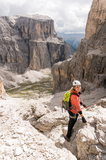 jovem montanhista feminina descendo uma íngreme Via Ferrata nas Dolomitas de Alta Badia, no norte da Itália, com grande paisagem atrás
 - Foto, Imagem