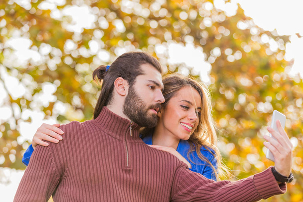 秋の公園で selfie を作るかわいいカップル/秋のシーズン. - 写真・画像