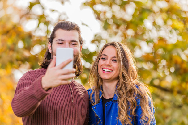 Cute couple making selfie in the park at autumn / fall season. - Foto, afbeelding