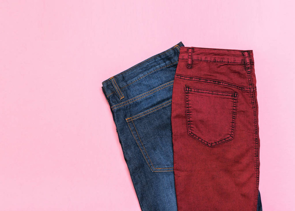 Classic blue men's jeans and purple denim skirt on pink background. The view from the top. Fashionable denim women's clothing. Denim women's clothing on colored background. Flat lay. - Photo, Image