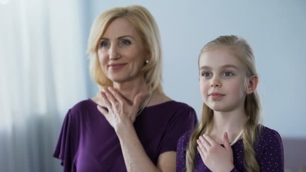 Blond grandmother and granddaughter with pearl necklaces looking in mirror - Imágenes, Vídeo