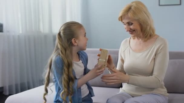 Pretty female grandchild giving gift to granny for birthday, family holidays - Materiał filmowy, wideo