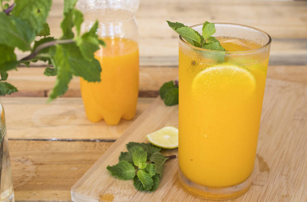 herbal healthy drinks cold orange juice for health care with peppermint leaf and lemon slice on background wooden - Photo, Image