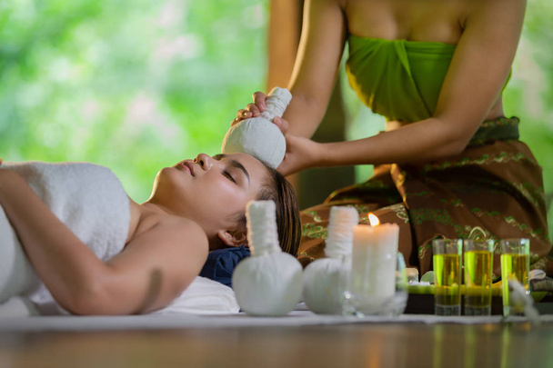 Молодая Азия красивая женщина во время массажа с спа-травяной компресс с маслом и травяной набор рядом с местом, расслабляющая и здоровая концепция
. - Фото, изображение
