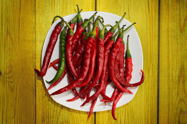 Punainen kuuma chili pippuri keltaisella puulla
 - Valokuva, kuva