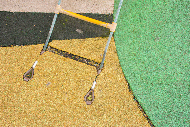 Fixation d'une échelle à corde à un revêtement en caoutchouc sur une aire de jeux pour enfants dans la rue
 - Photo, image