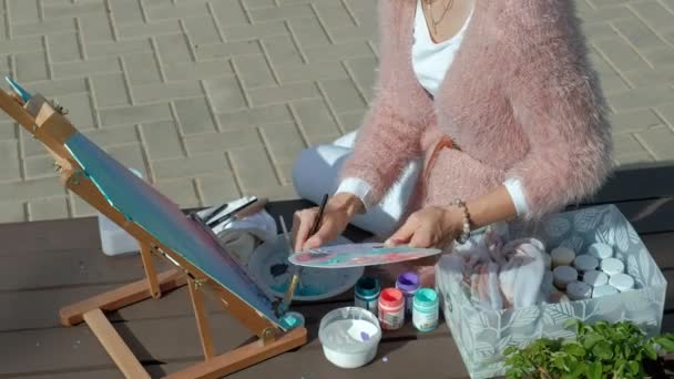 Красива жінка з рудим волоссям, малює картину на полотні, яка стоїть на мольберті. Дама знаходиться на відкритому повітрі біля озера річки, вона витягує з життя
 - Кадри, відео