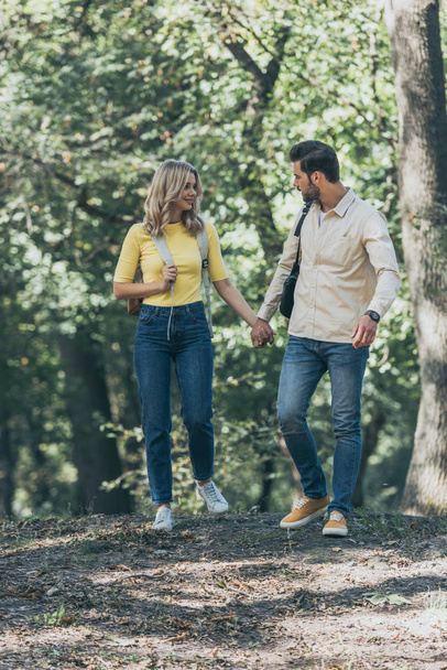 young couple holding hands while walking in autumn park together - Fotoğraf, Görsel