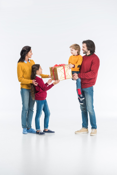 happy mother with daughter presenting wrapped gift to father with son isolated on white  - Fotoğraf, Görsel