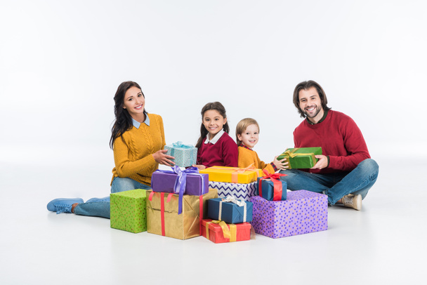 familia sonriente con cajas de regalo envueltas aisladas en blanco
  - Foto, imagen