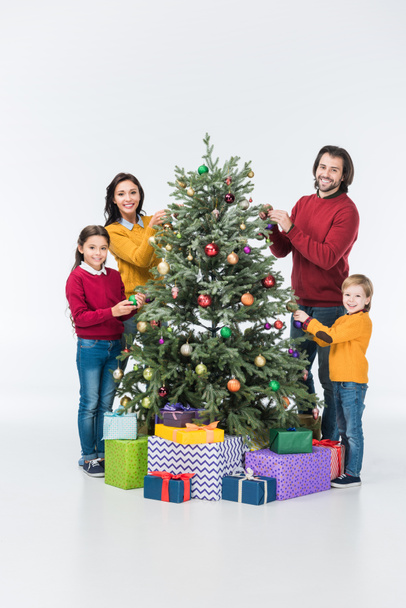 Happy family decorating christmas tree with glass balls and looking at camera isolated on white - Foto, immagini