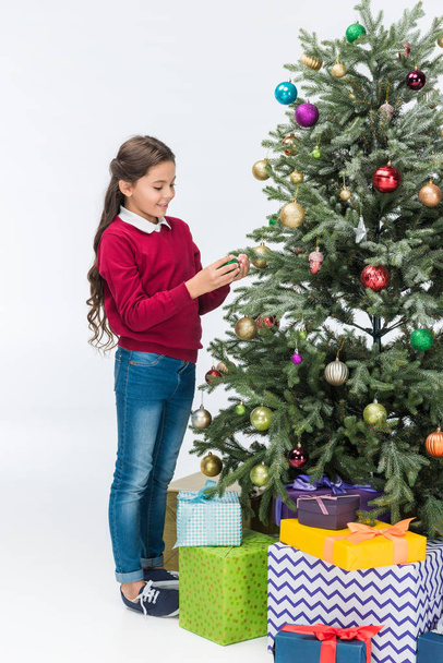 Happy child decorating christmas tree with presents isolated on white - 写真・画像