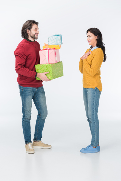 smiling husband presenting wrapped gifts to wife isolated on white  - Fotó, kép