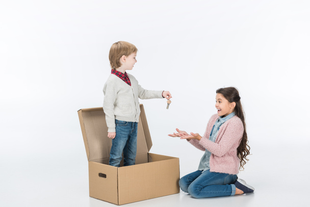 boy giving key from new house to surprised sister ready to move into new house isolated on white  - Photo, Image