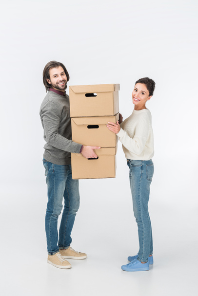 couple holding stack of cardboard boxes and looking at camera isolated on white - Photo, Image