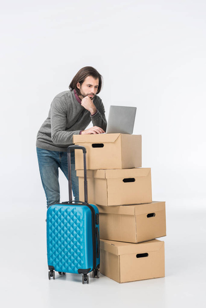 man using laptop on cardboard boxes isolated on white - Foto, imagen