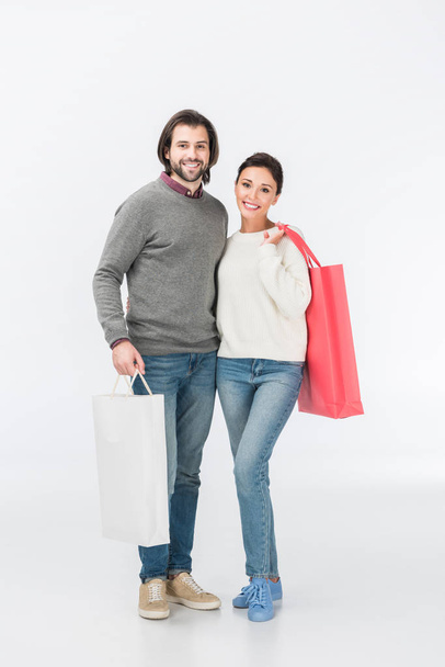 smiling couple with shopping bags isolated on white - Photo, Image