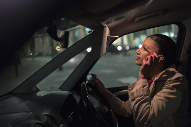Mujer de negocios que aplica rímel en el coche por la noche
 - Foto, Imagen