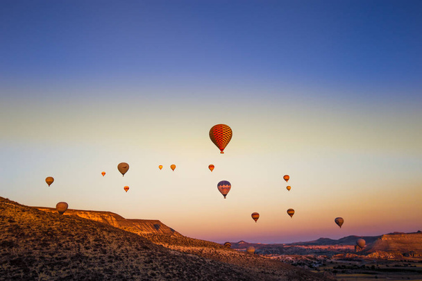 Красочные воздушные шары, летящие над долиной в Каппадокии, Анатолии, Турции. Большая туристическая достопримечательность Каппадокии лучшие места для полета с воздушными шарами горячим воздухом.
 - Фото, изображение
