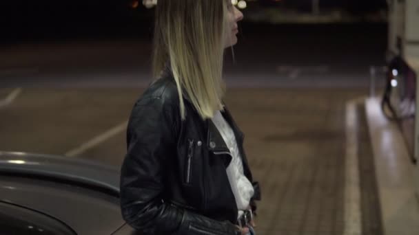 Car fuel. Attractive caucasian woman standing near her car while fuelling it. Blonde woman leaning on car. Nighttime - Footage, Video