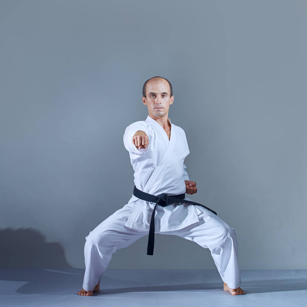 Zawodnik uderza ręką w szafie karate na ciemnym tle - Zdjęcie, obraz