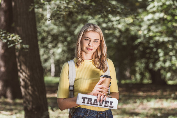 retrato de la joven rubia con café para ir y periódico de viaje en el parque
 - Foto, imagen