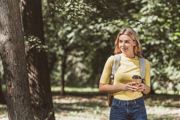 portrait of young woman with coffee to go walking alone in park - Zdjęcie, obraz