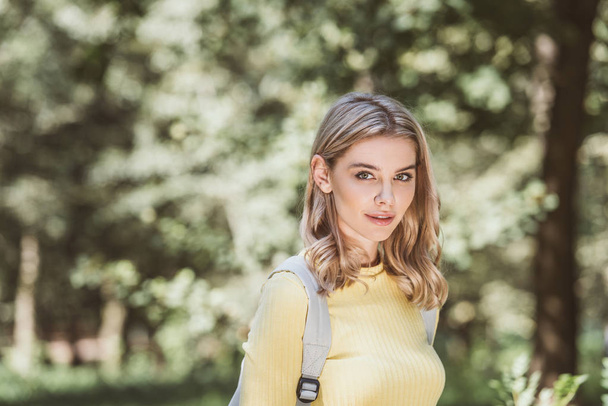 portrait of beautiful young woman with backpack in park - Foto, Imagen