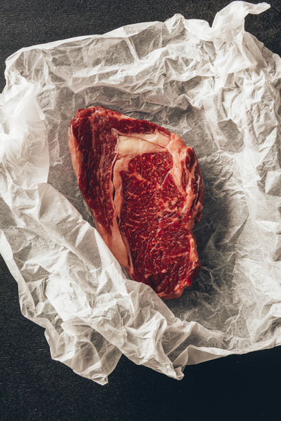 elevated view of raw meat steak on baking paper in kitchen  - Fotoğraf, Görsel