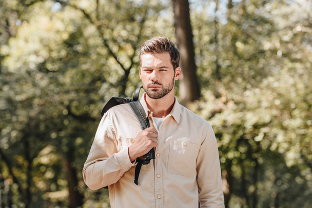 portrait of pensive young man with backpack in autumn park - Φωτογραφία, εικόνα