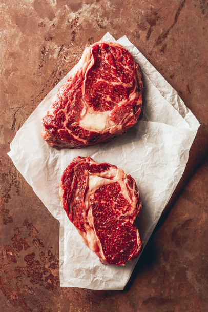 top view of two raw steaks on baking paper in kitchen - 写真・画像