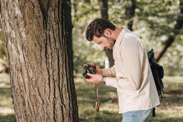 side view of young traveler with photo camera in park - Valokuva, kuva