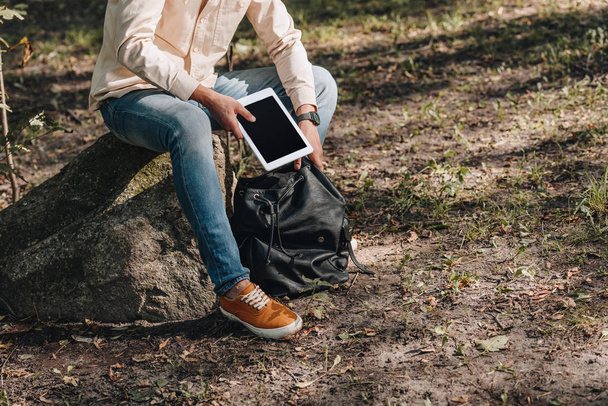 částečný pohled člověka s batohem a digitální tablet v parku - Fotografie, Obrázek
