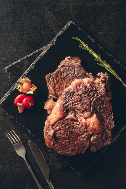 pohled chutné steaky pečené s rozmarýnem a berry na krájecí desky v kuchyni - Fotografie, Obrázek