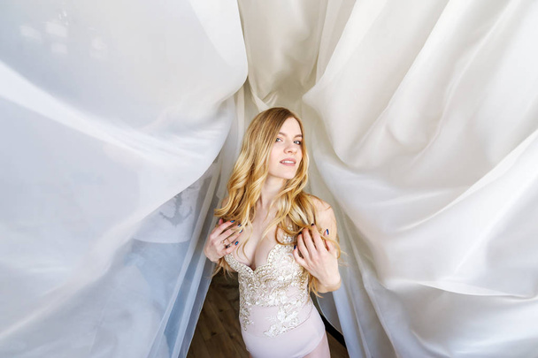 Young pregnant woman in underwear poses for the camera against the background of a white curtain. Motherhood concept, pregnancy concept, happiness concept. Closeup portrait  - Foto, immagini