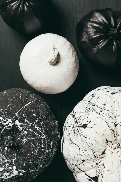 top view of black and white pumpkins with paint splatters on dark halloween background - Foto, afbeelding