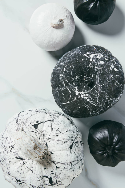 top view of decorative black and white pumpkins with paint splatters, halloween composition - Foto, immagini