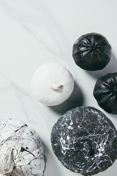 top view of decorative black and white pumpkins with paint splatters for halloween party - Foto, afbeelding